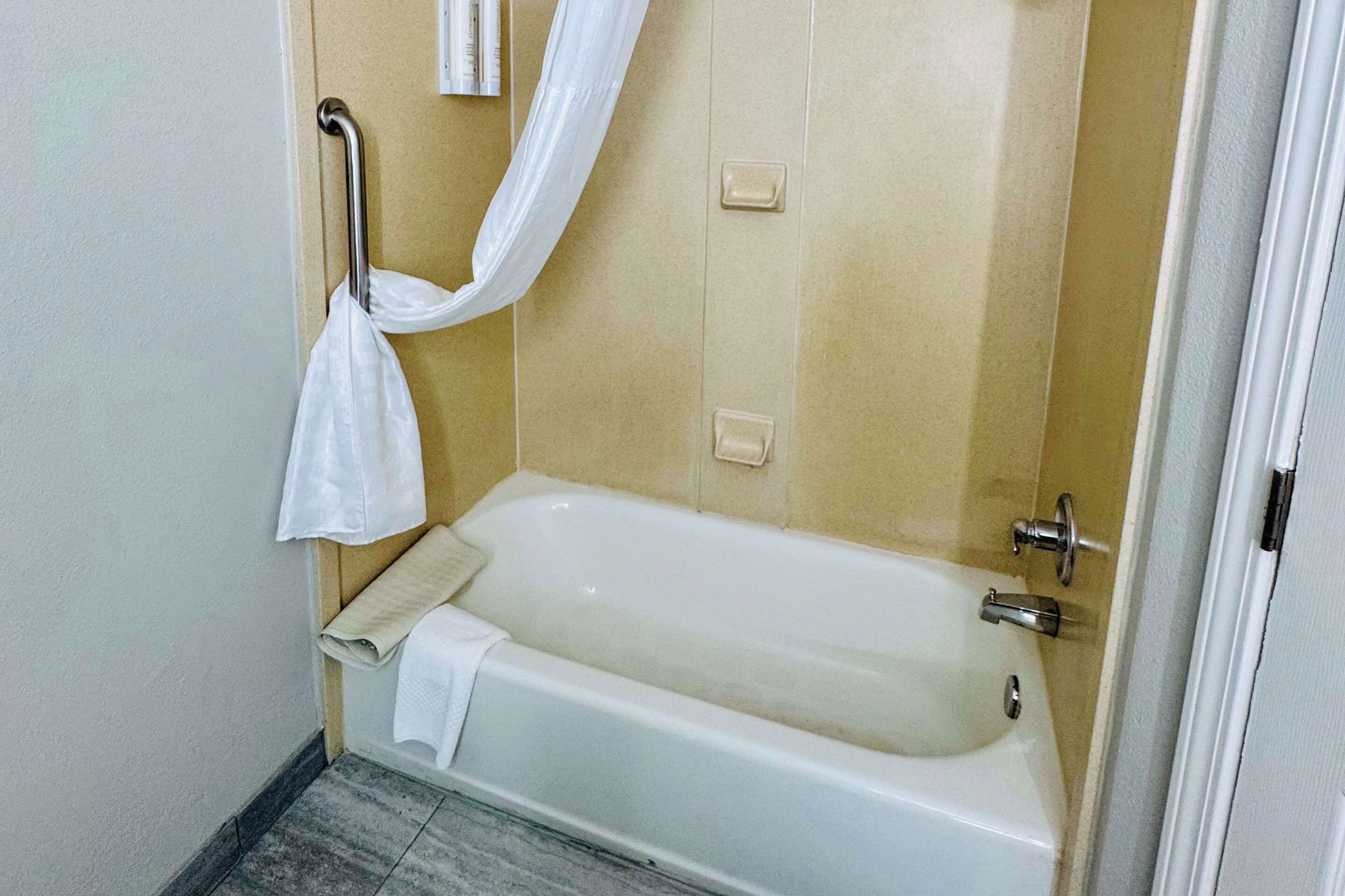 Un baño con bañera, toallero y cortina de ducha.
