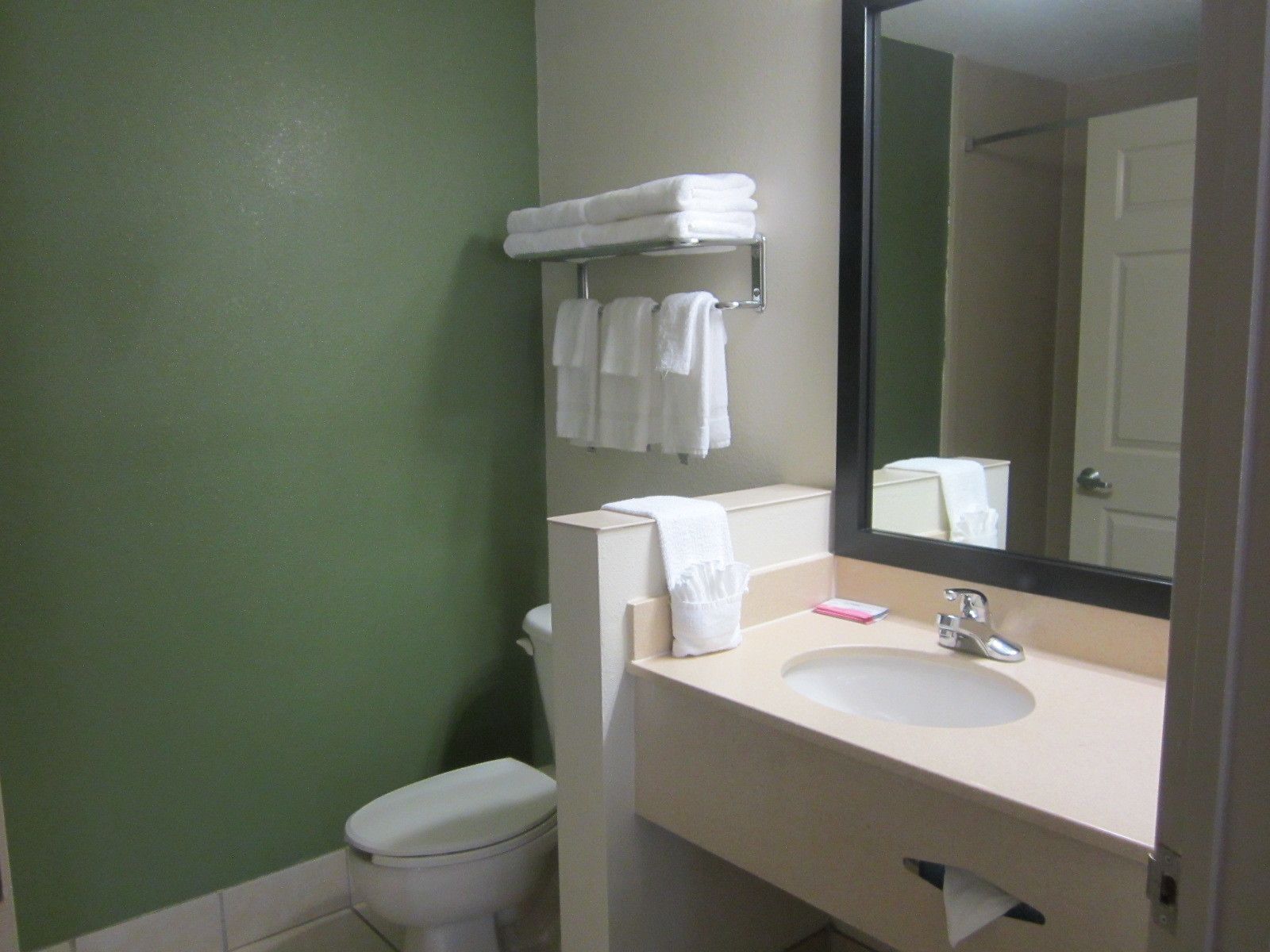 A bathroom with a toilet, sink, and a towel rack with folded towels.