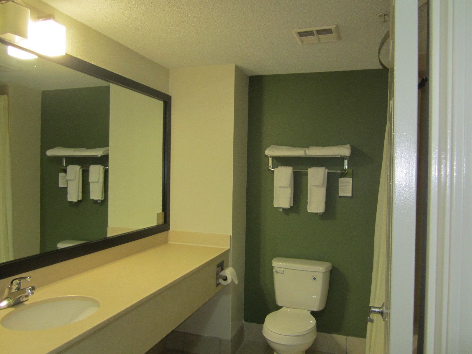 A bathroom with a sink, mirror, toilet, and towel rack.