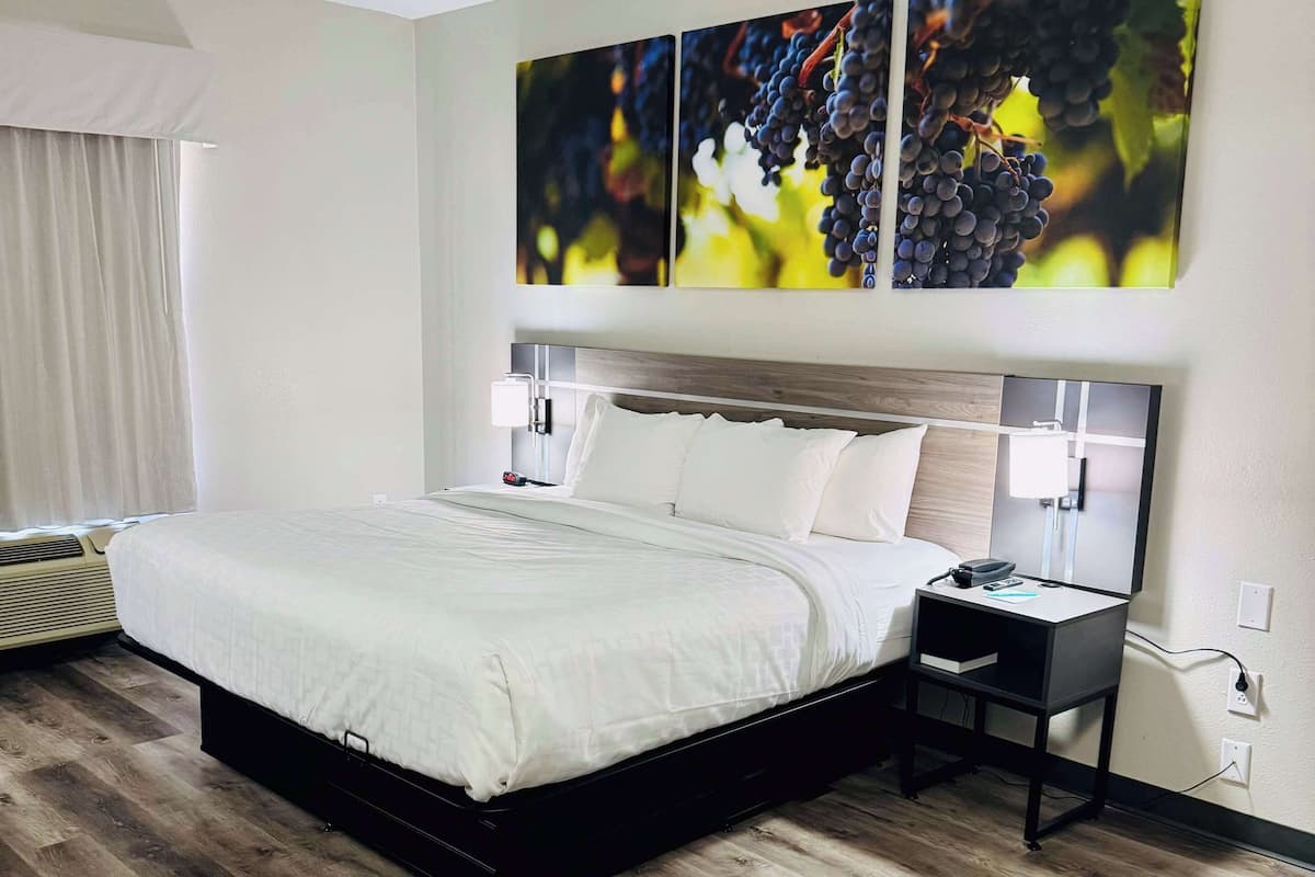 A modern hotel room with a large bed, bedside tables, and a wall-mounted TV.