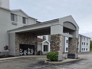 Un bâtiment moderne doté d’un porche, de piliers en pierre et d’une porte de garage au motif décoratif.