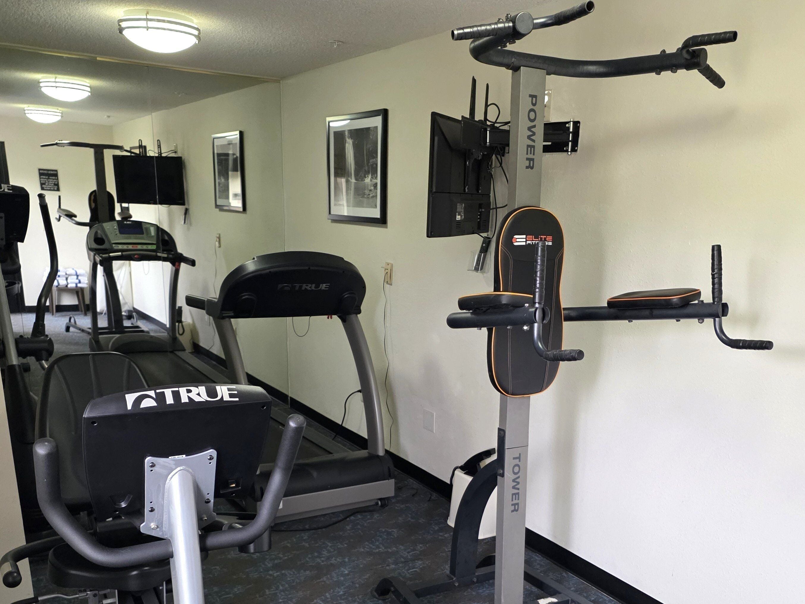 A gym with treadmills, a stair climber, and a wall-mounted exercise machine.