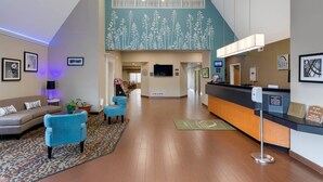 A hotel lobby with a reception desk, seating area, and a large window with a floral mural.
