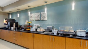A modern kitchen with wooden cabinets, a coffee machine, a toaster, and a slow cooker.