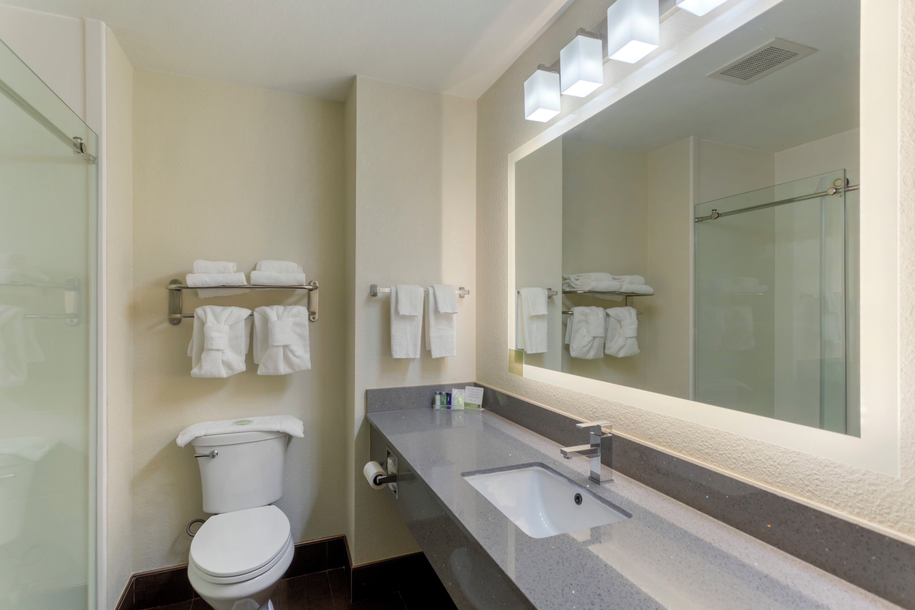 A modern bathroom with a toilet, sink, and glass shower enclosure.