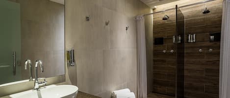 Un baño moderno con un lavamanos grande, cabina de ducha de vidrio y un espejo.