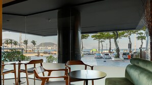 Un espace de détente intérieur moderne, avec vue sur la plage et le paysage urbain.