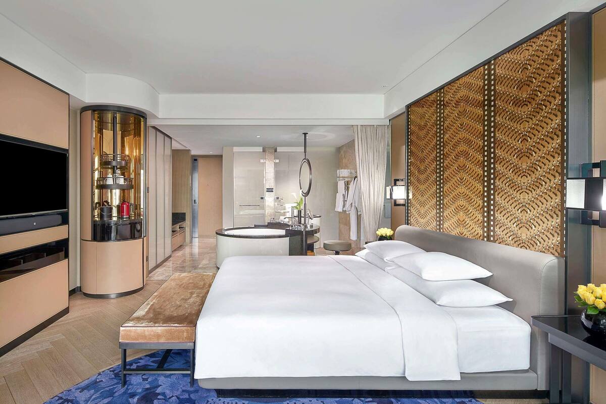 Una habitación de hotel moderna con una cama grande, televisión, minibar y baño con bañera.