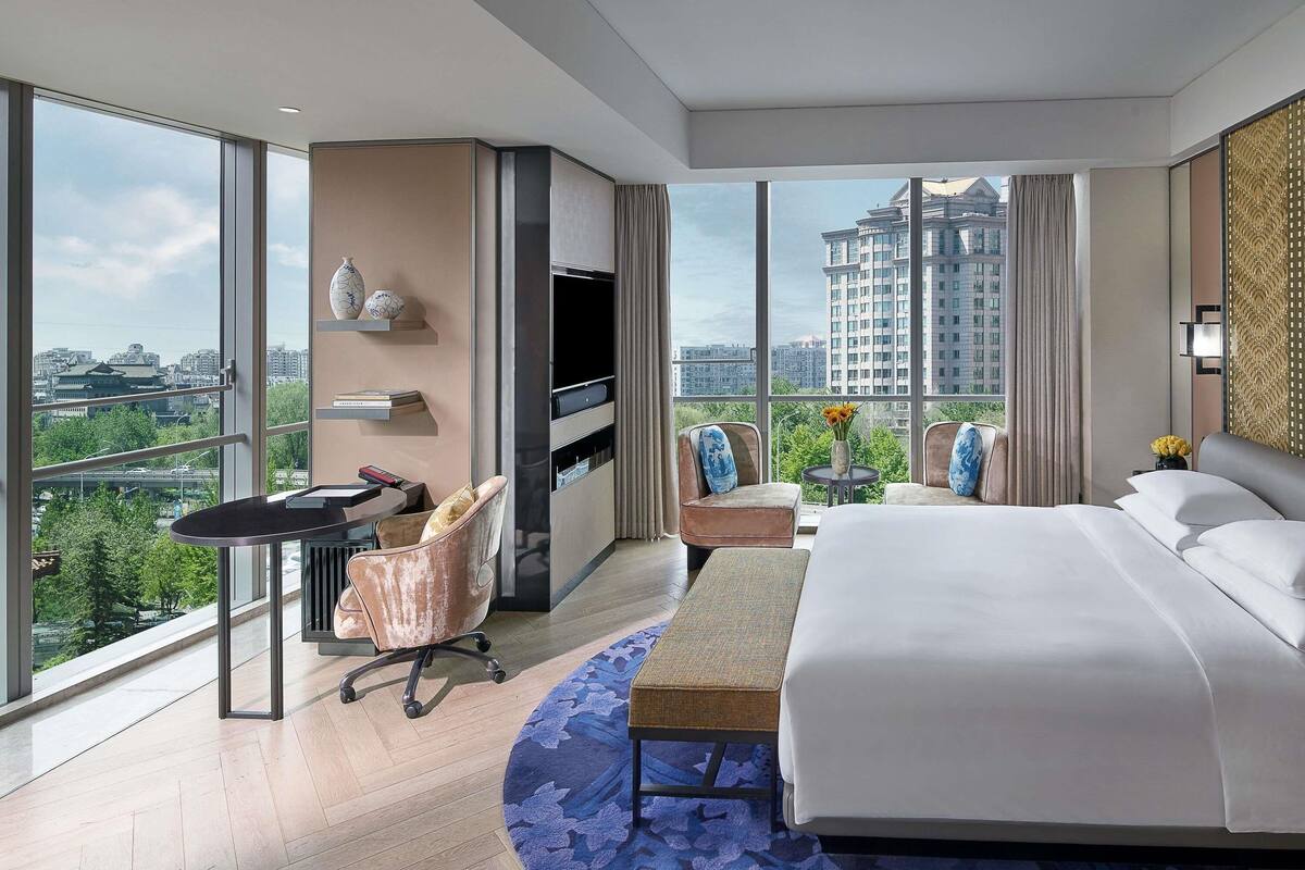Una habitación de hotel moderna con una cama grande, un escritorio, una silla y un televisor.