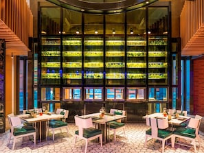 Enjoy communal dining in a stylish space with semi-circular tables and green cushioned chairs.