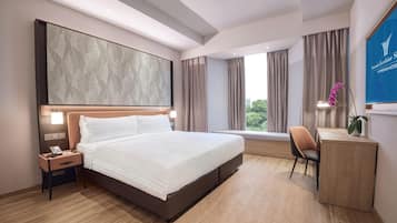 A hotel room with a large bed, a desk, a chair, and a view of the outdoors.