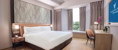 A hotel room with a large bed, a desk, a chair, and a view of the outdoors.