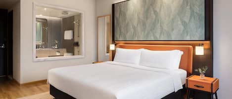 A modern hotel room with a large bed, a nightstand, a mirror, and a large abstract painting above the bed.