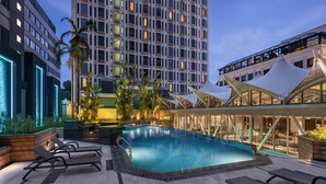 A rooftop pool area with lounge chairs, a swimming pool, and modern buildings in the background.