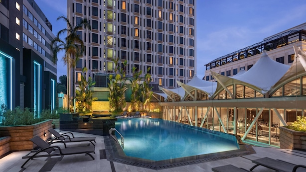A rooftop pool area with lounge chairs, a swimming pool, and modern buildings in the background. - Wyndham Singapore Hotel (Singapore)
