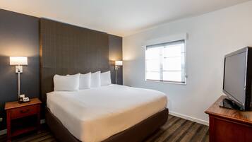 A hotel room with a large bed, bedside lamps, a television, and a window.