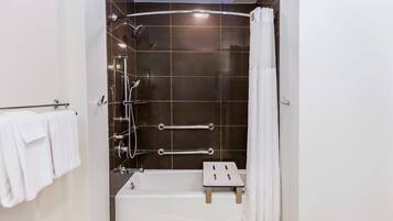 A modern bathroom with a bathtub, shower, and grab bars.