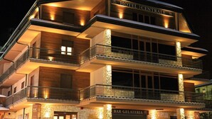 Un hotel de varios pisos con balcones y un bar llamado "BAR GELATERIA".