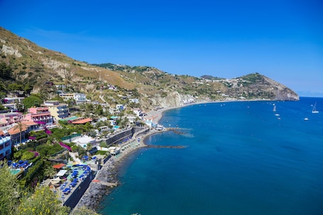 A coastal town with a beach, houses, and a clear blue sea.