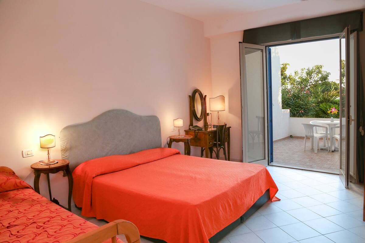 A hotel room with a bed, a desk, a chair, and a view of the outside.