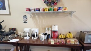 Ein Frühstücksbuffet mit Kaffeeautomaten, Müsli, Bananen und einem Toaster.