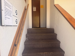 A staircase with a wooden handrail leading to a door with a sign indicating 'Restrooms' and 'Employee Lounge.' - Autumn's Inn Roundup MT near Hwy 12 (Roundup)