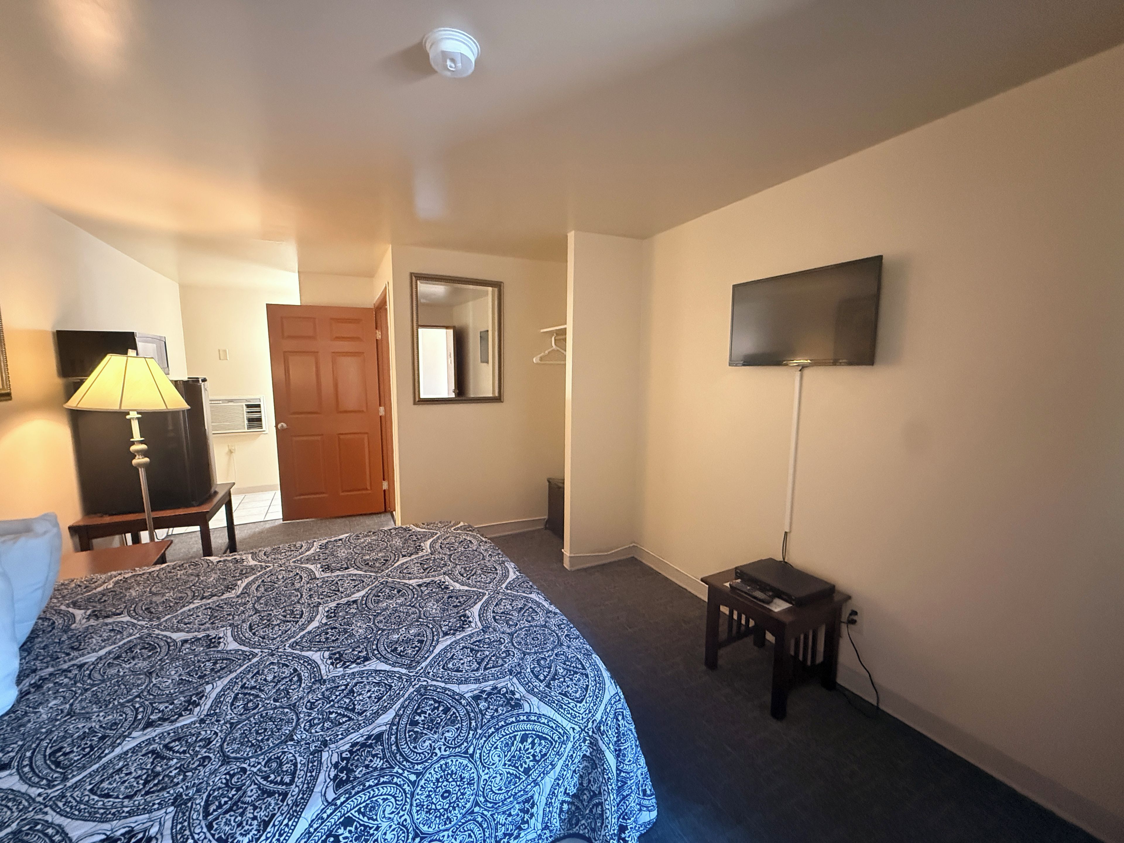 Una habitación de hotel con una cama, un escritorio, una silla, un televisor y una puerta.