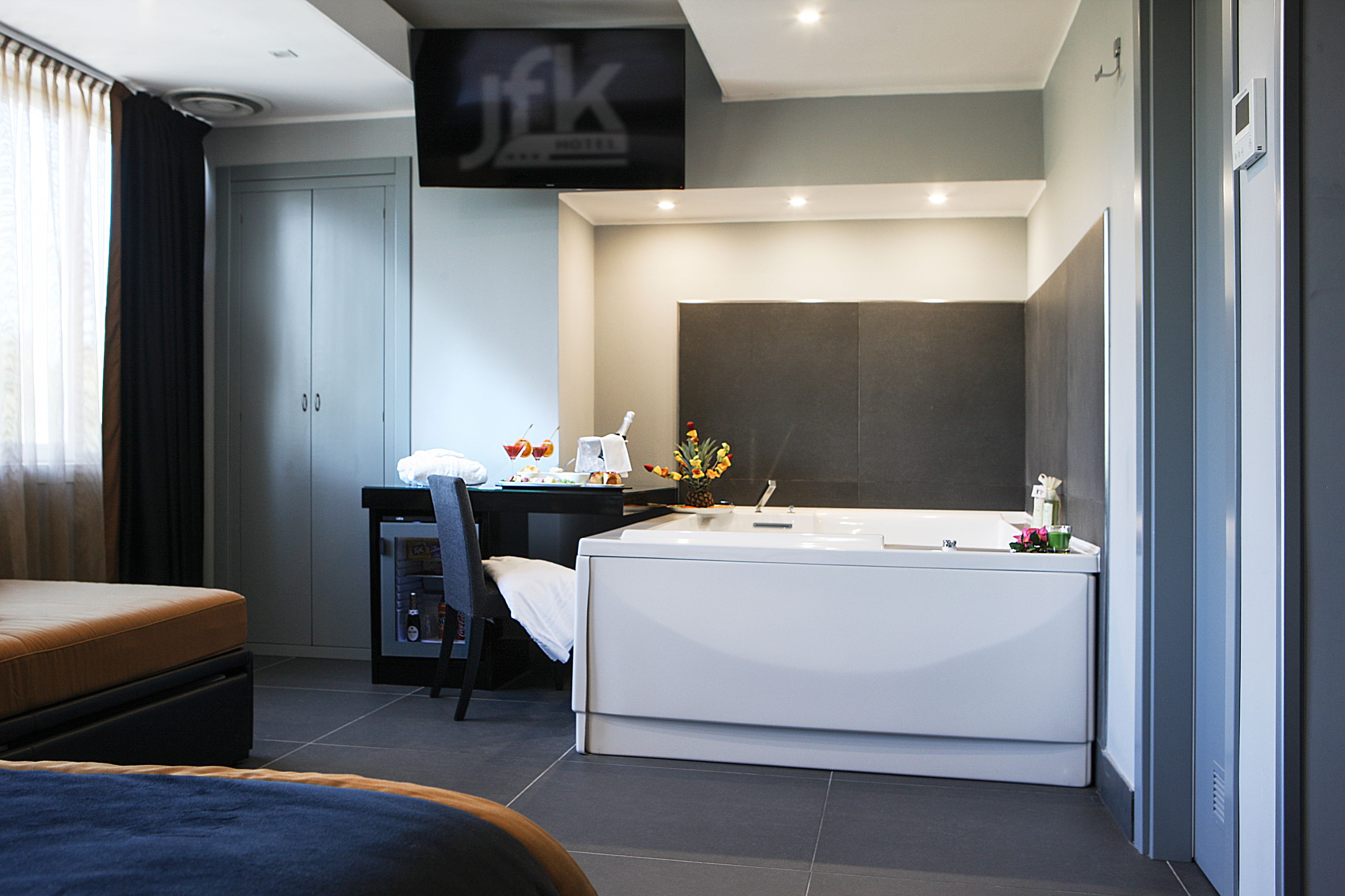 Ein modernes Hotelzimmer mit Bett, Schreibtisch und einer großzügigen Badewanne.