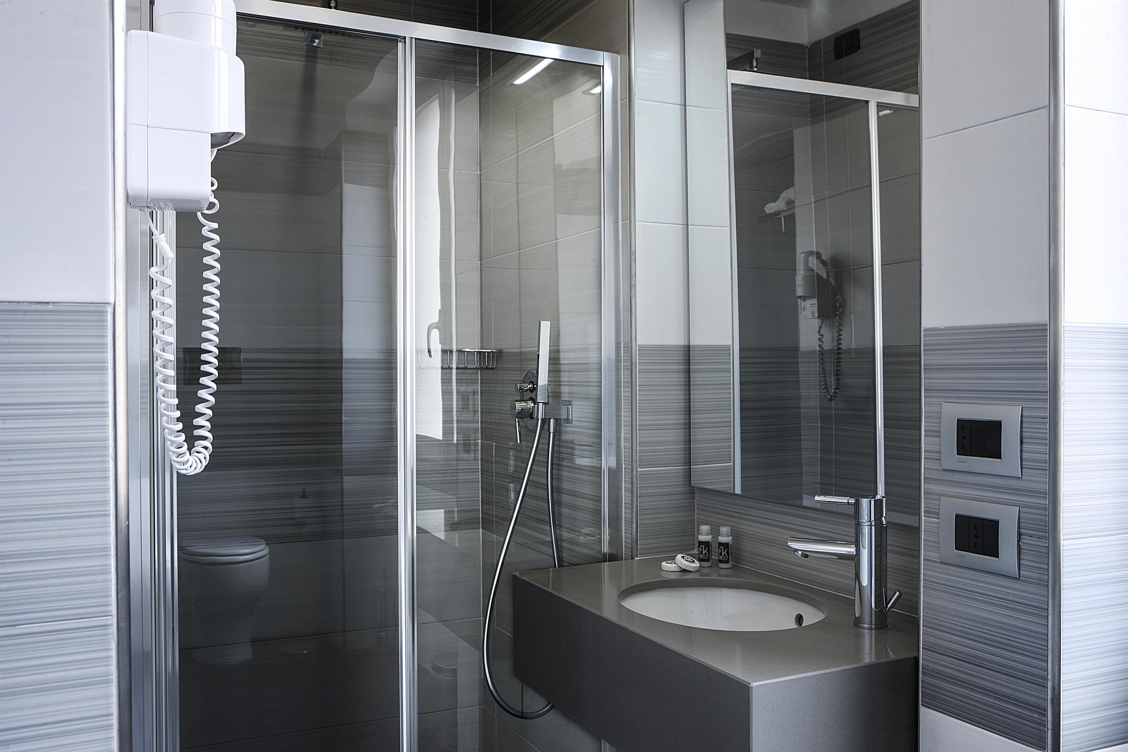 A modern bathroom with a glass-enclosed shower, a sink, and a mirror.