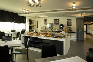 A modern hotel lobby with a central buffet area, black and white decor, and a spacious layout. - Best Western JFK Hotel (Naples)