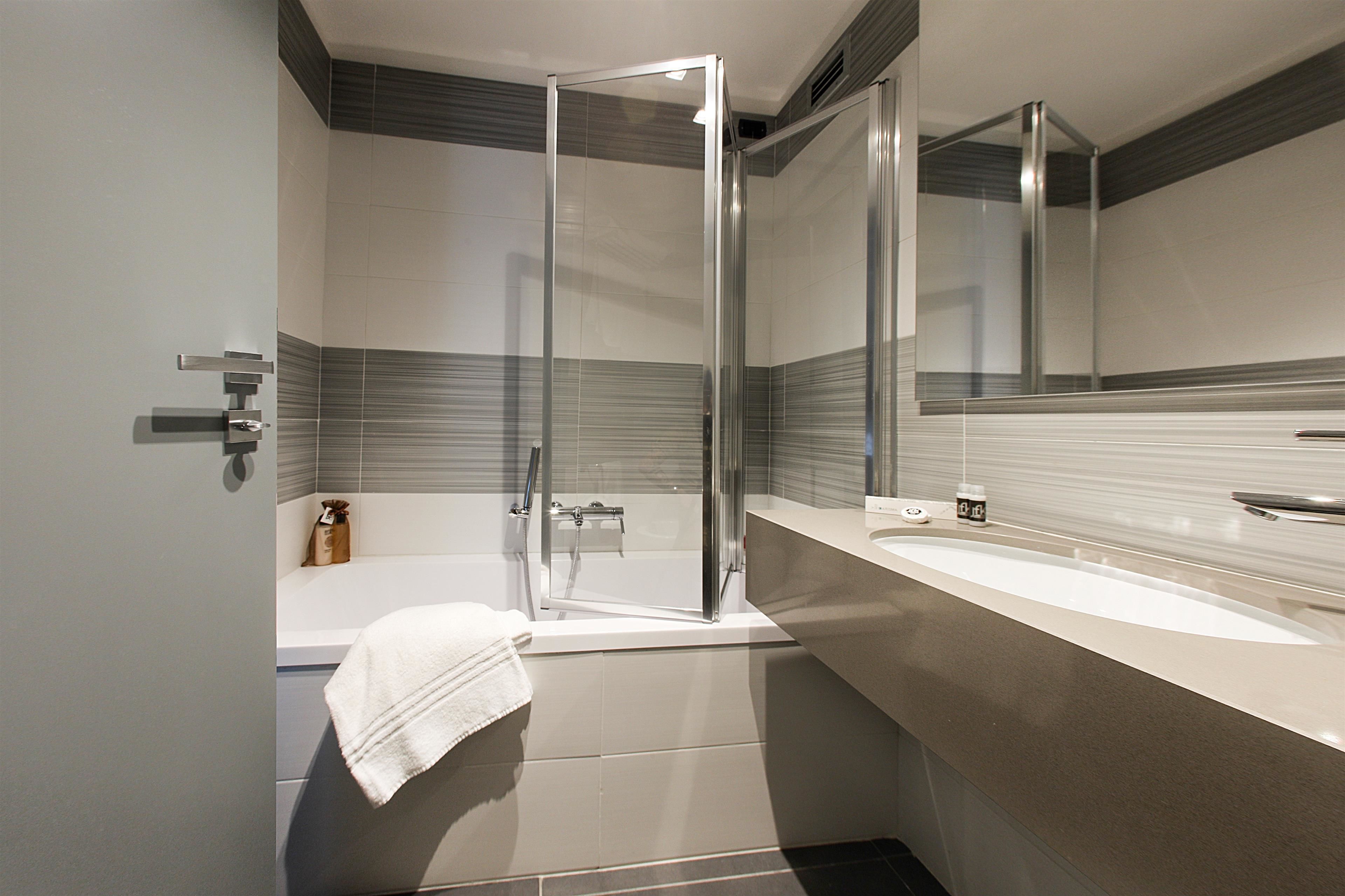 A modern bathroom with a glass-enclosed shower, a bathtub, and a large mirror above the sink.