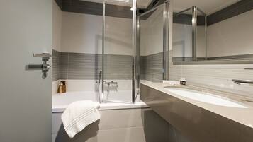 A modern bathroom with a glass-enclosed shower, a bathtub, and a large mirror above the sink.