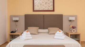 A hotel room with a large bed, two nightstands, a telephone, and a framed picture on the wall.