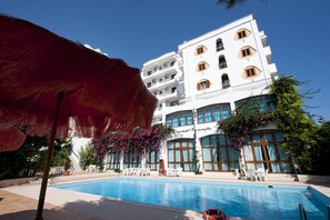 Una piscina al aire libre, sombrillas, tumbonas
