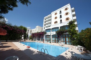 Una piscina al aire libre, sombrillas, sillones reclinables de piscina