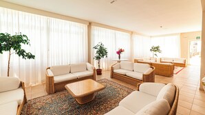 Un salón amplio con un ventanal grande, una mesa de centro y varias zonas de estar con sofás y sillones.