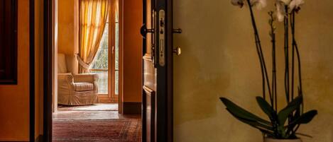 A doorway leading to a room with a view of a balcony, a chair, and a potted orchid plant.