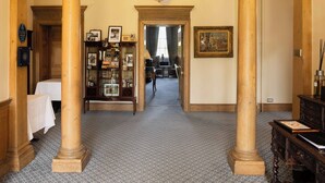 A grand hallway with a high ceiling, a chandelier, and classical architecture including columns and an archway. - Culloden House Hotel (Inverness)