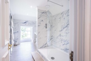 A modern bathroom with a glass-enclosed shower, marble walls, and a view of the outdoors. - Culloden House Hotel (Inverness)