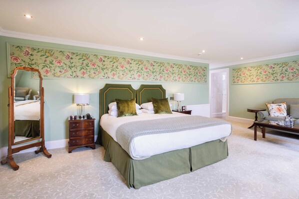 A bedroom with a large bed, two bedside tables with lamps, a dresser, and a mirror.