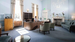 A hotel lobby with a reception desk, seating area, and a fireplace. - Culloden House Hotel (Inverness)
