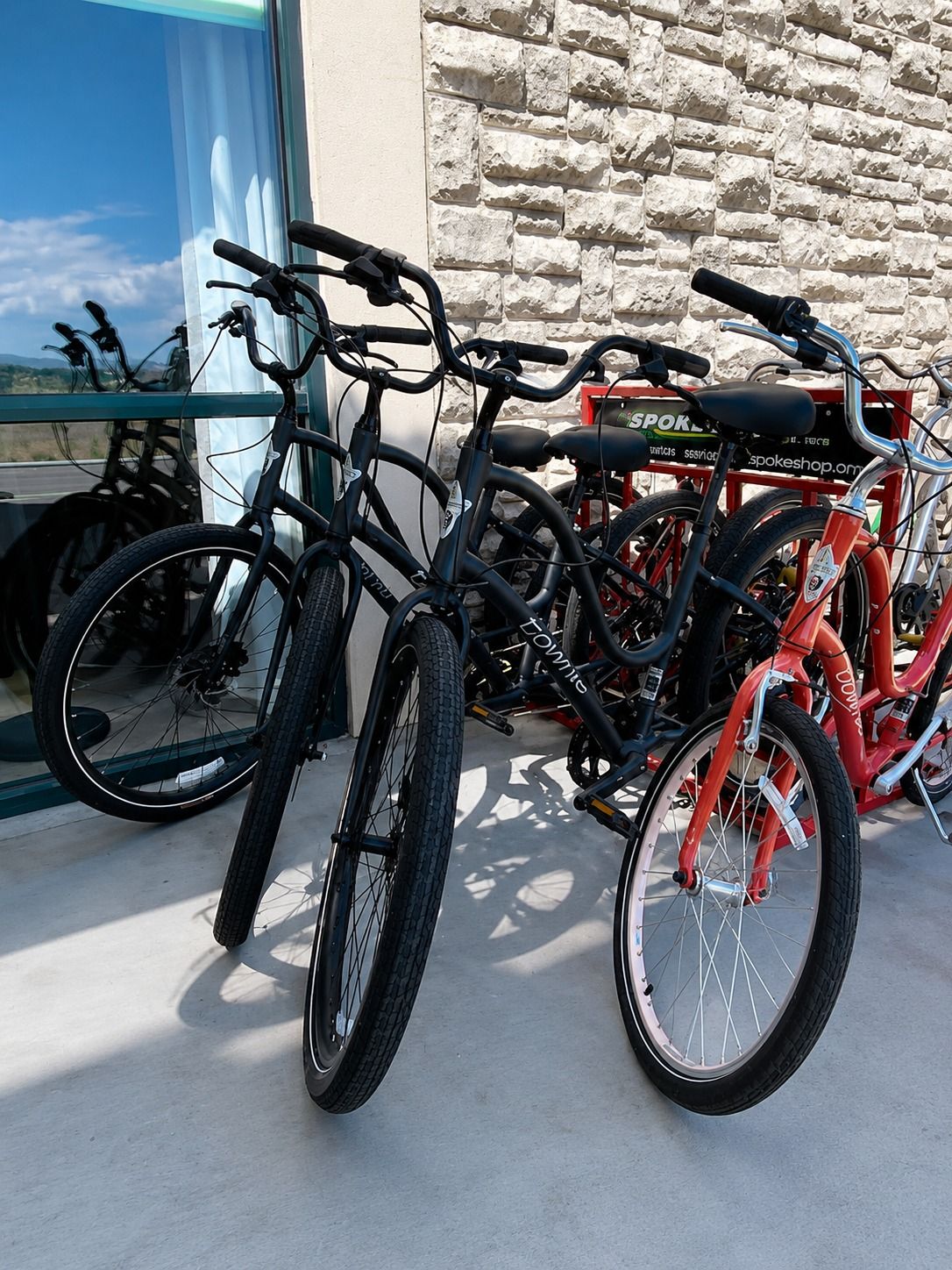 A row of bicycles parked against a stone wall, with a clear sky visible through a window.