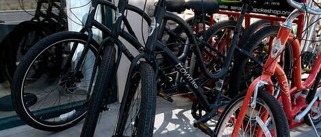A row of bicycles parked against a stone wall, with a clear sky visible through a window.