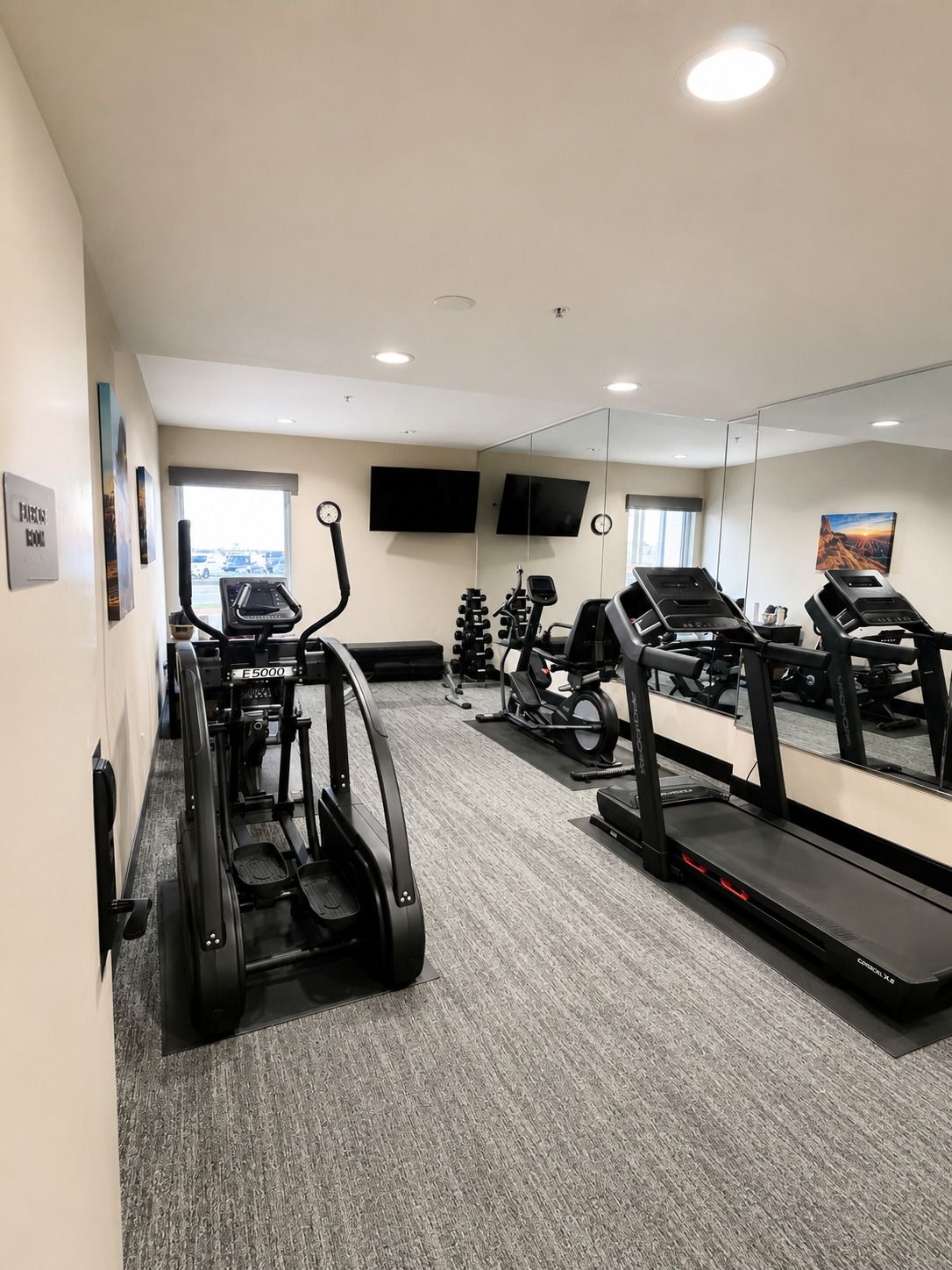 Ein Fitnessraum mit Laufbändern, einem Ergometer und einer Gewichtbank.