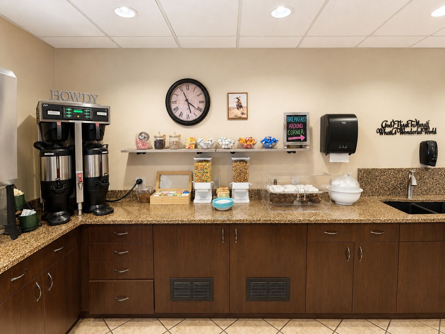 A kitchen area with a coffee machine, a clock, and various food items on the counter.