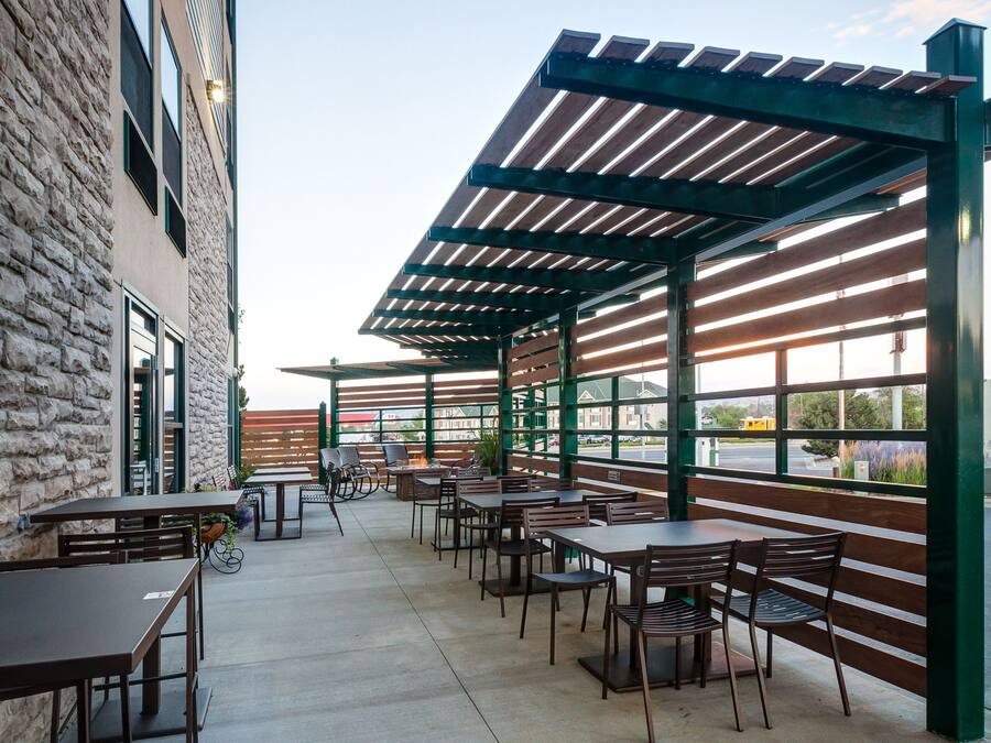 An outdoor patio with tables and chairs, a pergola, and a view of the street.