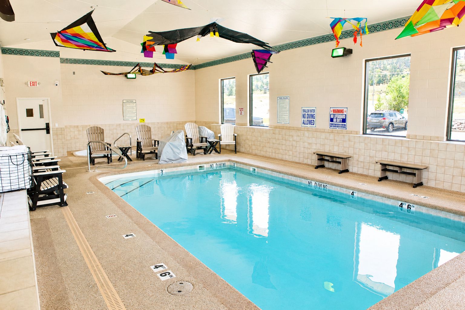 A swimming pool with no diving allowed, surrounded by lounge chairs and covered seating.
