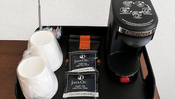 A tray with a coffee maker, two cups, and two packets of JavaOne coffee pods.