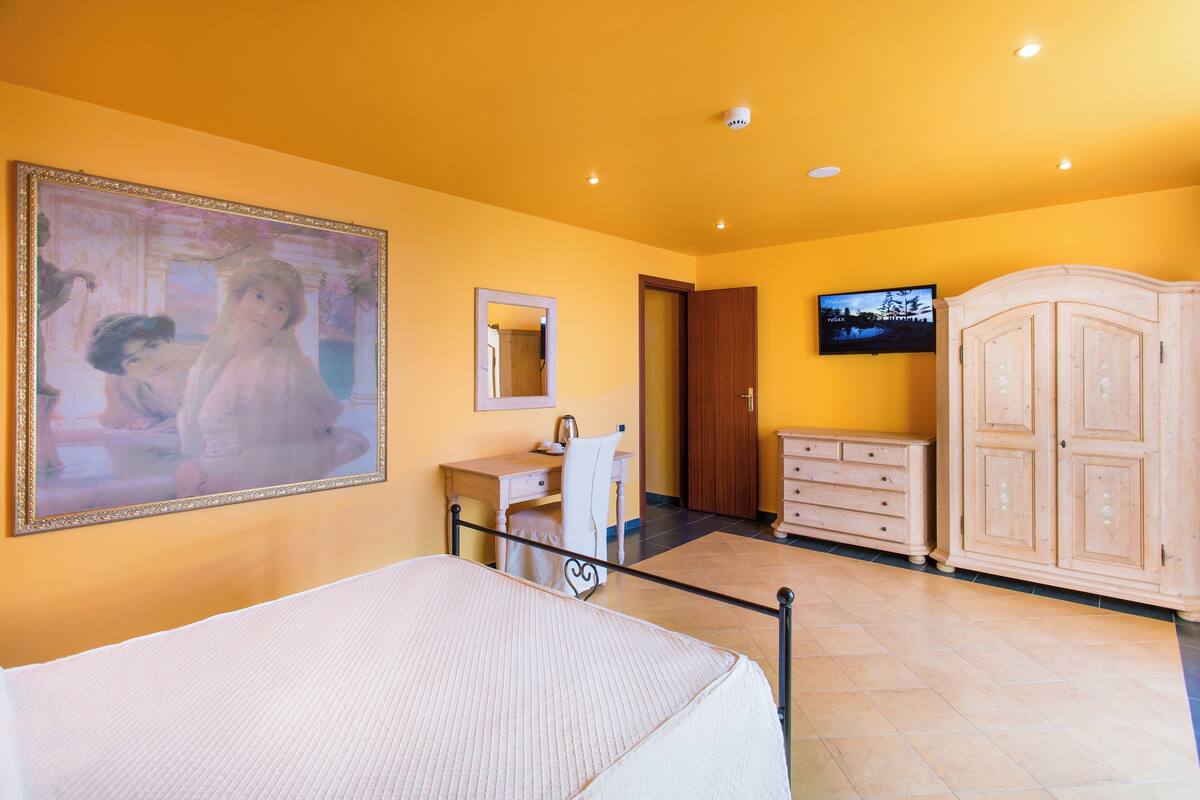 Ein Schlafzimmer mit Bett, Schreibtisch, Stuhl, Fernseher und Kleiderschrank.
