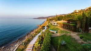 A coastal property with a pathway leading to a boat, a grassy area, and a view of the sea.